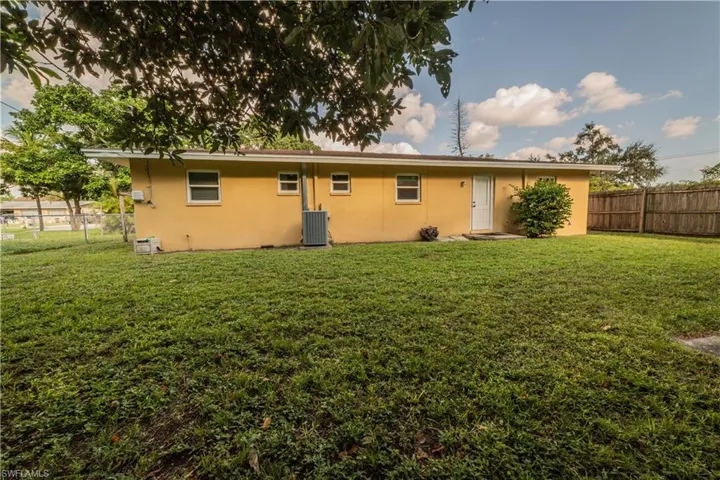 Rear view of house featuring central AC and a lawn