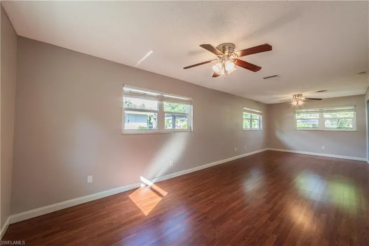 Spare room with a wealth of natural light, ceiling fan, and dark hardwood / wood-style floors
