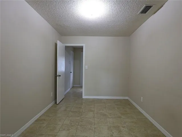 Empty room featuring a textured ceiling and light tile patterned flooring