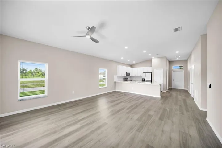 Unfurnished living room with ceiling fan, lofted ceiling, and light hardwood / wood-style floors