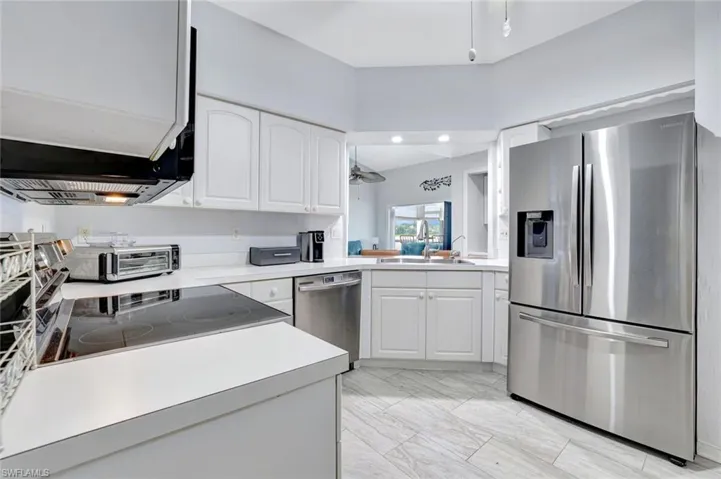 Kitchen featuring stainless steel appliances, white cabinets, and light countertops