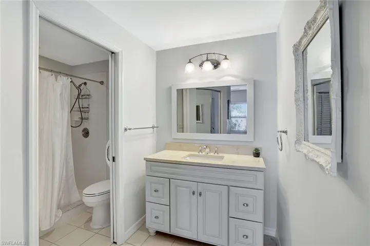 Bathroom featuring vanity, light tile patterned floors, and tiled shower