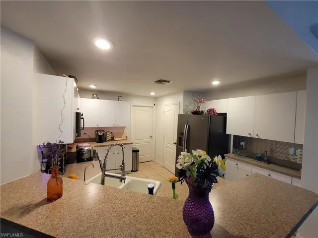 Kitchen with white cabinets, kitchen peninsula, stainless steel appliances, tasteful backsplash, and sink