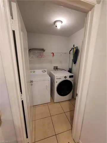 Laundry area with hookup for a washing machine, washing machine and clothes dryer, and light tile floors