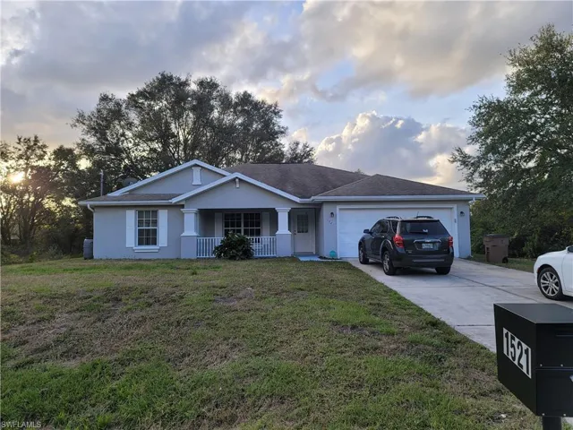 Ranch-style house featuring a garage and a front lawn