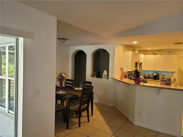 Dining space with vaulted ceiling and light tile floors