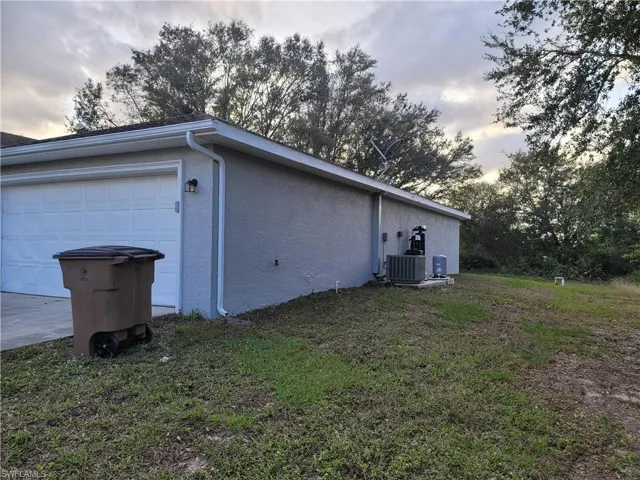 View of side of home with a garage and central air condition unit