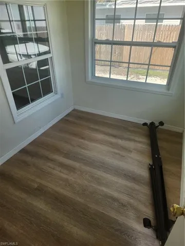 Spare room with dark wood-style floors and baseboards
