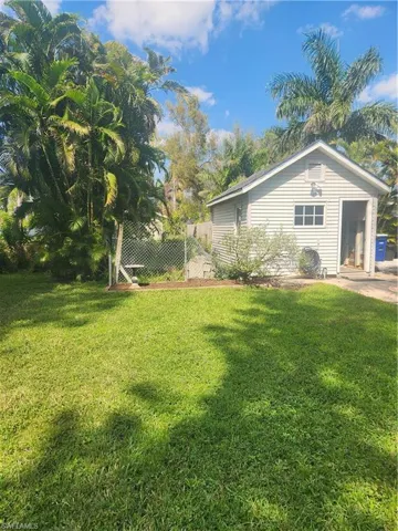 View of property exterior with a lawn and fence