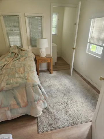 Bedroom with multiple windows, baseboards, and wood finished floors