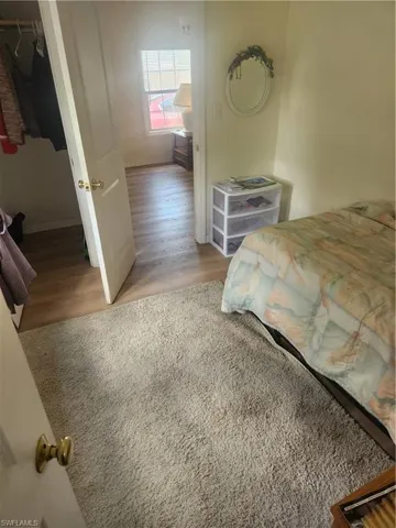 Bedroom featuring a closet, baseboards, a walk in closet, and wood finished floors