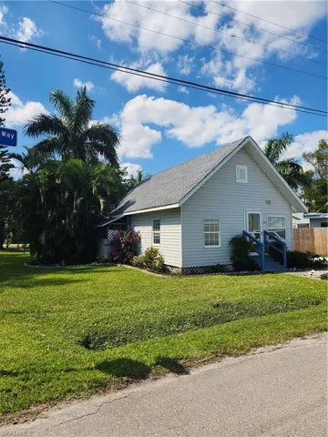 View of side of home featuring a shingled roof, a yard, and fence