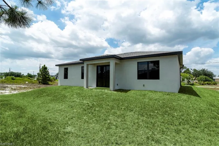 Back of property featuring stucco siding, a lawn, and french doors