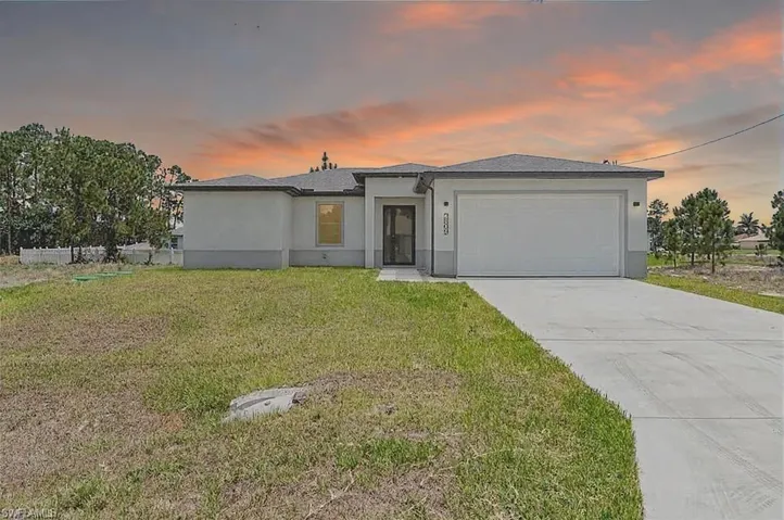 View of front of house featuring a garage, a front lawn, concrete driveway, and stucco siding