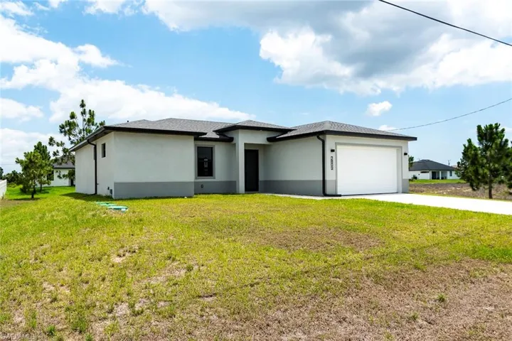 Prairie-style house featuring concrete driveway, a garage, a front yard, and stucco siding