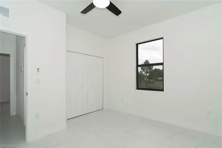 Unfurnished bedroom with light marble finish floors, a closet, and ceiling fan