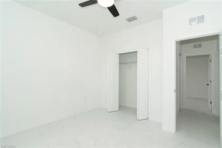 Unfurnished bedroom featuring light marble finish floors, a closet, and ceiling fan