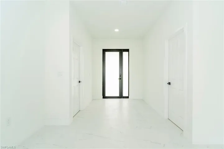 Hall featuring light marble finish flooring and recessed lighting