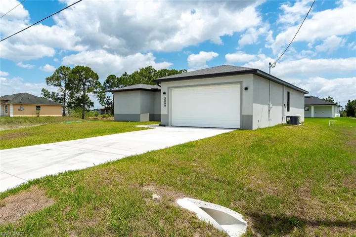 View of property exterior featuring stucco siding, a yard, concrete driveway, and a garage