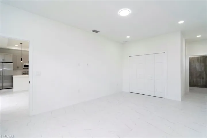 Unfurnished bedroom featuring recessed lighting, high end fridge, light marble finish flooring, and a closet