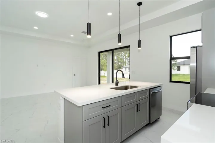 Kitchen with light marble finish flooring, hanging light fixtures, recessed lighting, plenty of natural light, and gray cabinetry