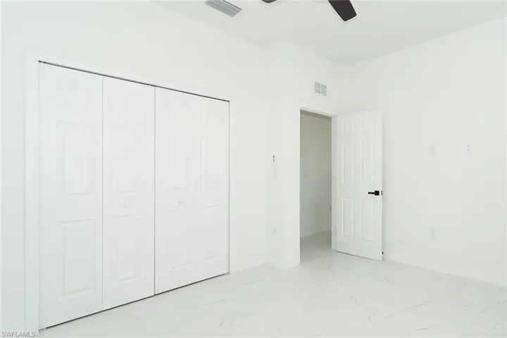Unfurnished bedroom featuring light marble finish floors, a closet, and a ceiling fan