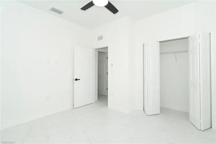 Unfurnished bedroom with light marble finish flooring, a closet, and ceiling fan
