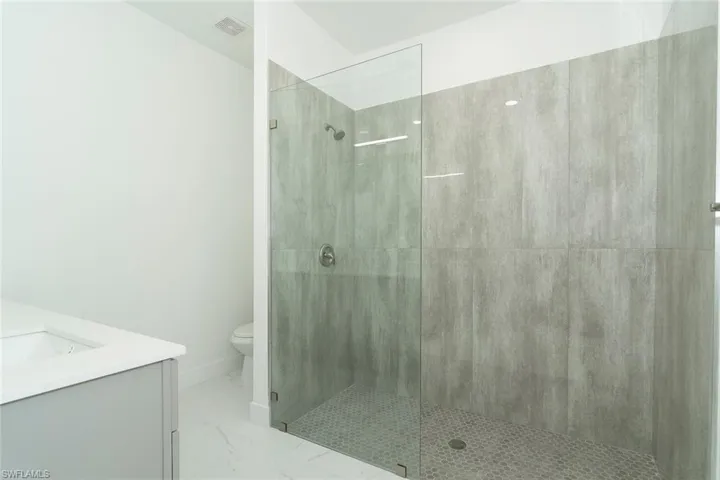 Full bathroom with walk in shower, vanity, and light marble finish floors