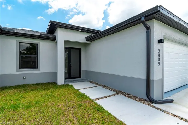 Entrance to property featuring stucco siding, a yard, and a garage