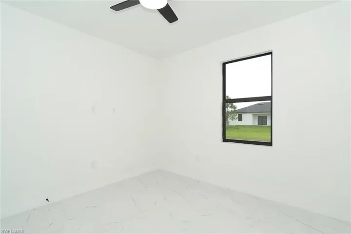 Spare room featuring marble finish flooring and ceiling fan