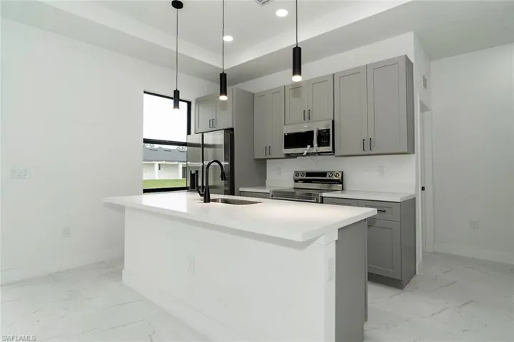 Kitchen with gray cabinets, light marble finish floors, appliances with stainless steel finishes, and recessed lighting