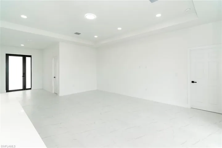 Unfurnished room featuring recessed lighting, light marble finish flooring, and a raised ceiling
