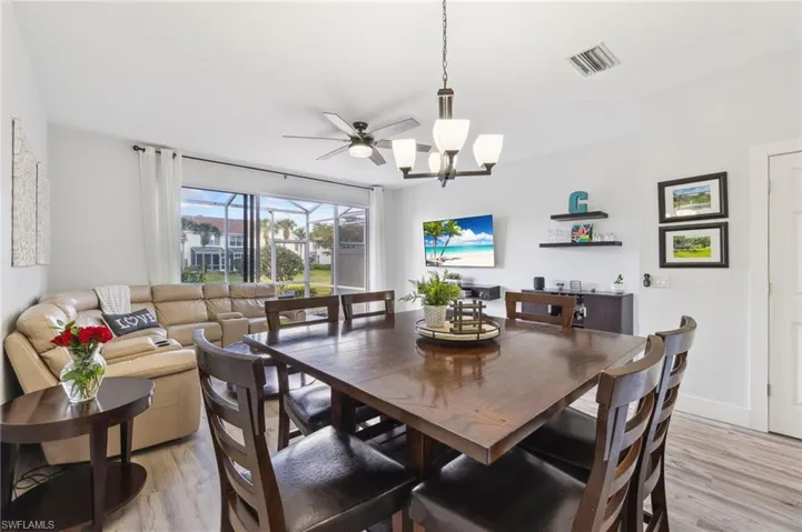Dining room with ceiling fan with notable chandelier and light hardwood / wood-style floors