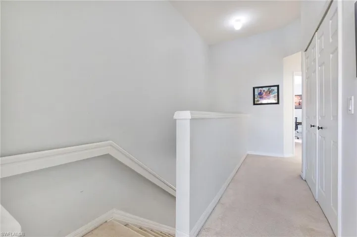 Corridor featuring light colored carpet