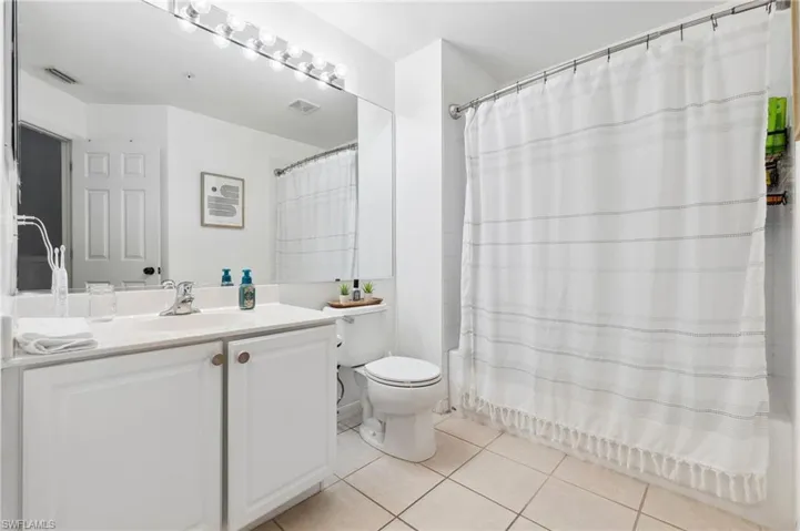 Full bathroom with tile patterned floors, toilet, vanity, and shower / bath combination with curtain