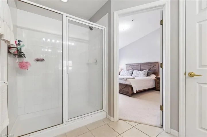 Bathroom featuring vaulted ceiling, tile patterned flooring, and an enclosed shower