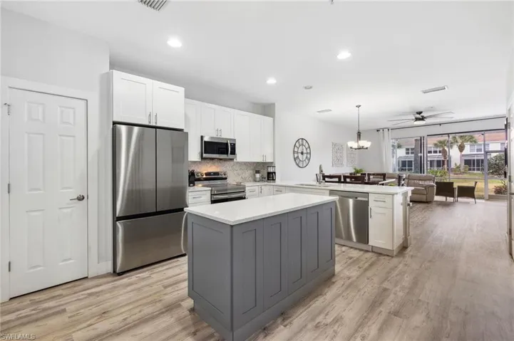 Kitchen featuring kitchen peninsula, a center island, sink, appliances with stainless steel finishes, and pendant lighting