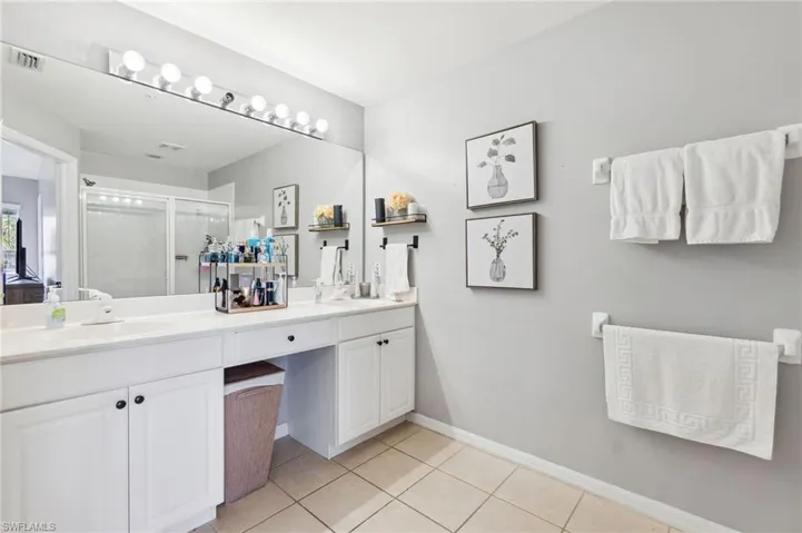 Bathroom featuring a shower with door, tile patterned flooring, and vanity