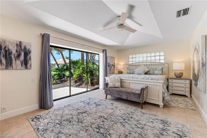 Tiled bedroom with multiple windows, ceiling fan, and access to outside