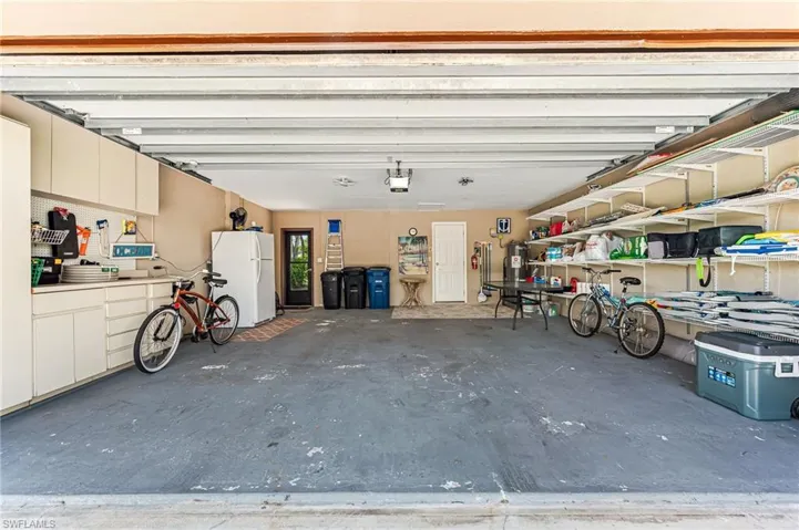 2 car garage featuring extra fridge along with plenty of. beah equipment and bikes