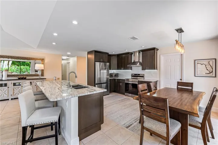 Kitchen featuring tasteful backsplash, wall chimney range hood, stainless steel appliances, pendant lighting, and sink