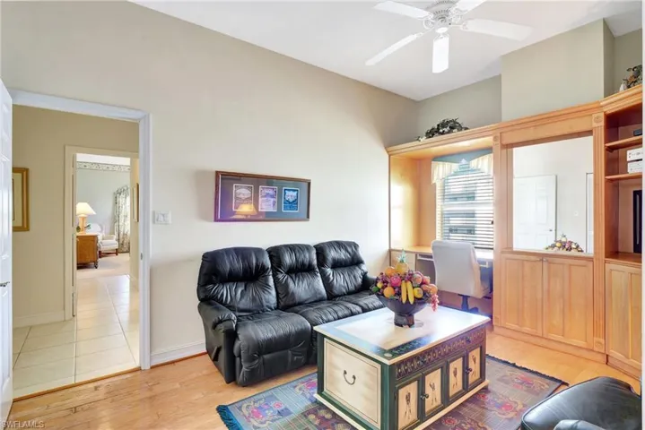 Living room with a ceiling fan, light wood-style flooring, and baseboards