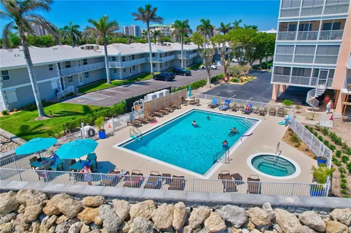 Community pool featuring a hot tub, fence, and a patio