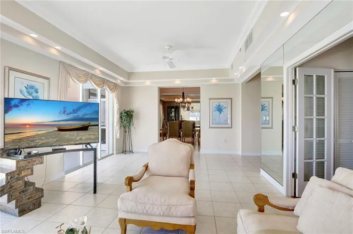 Living room featuring light tile patterned floors, ceiling fan with notable chandelier, baseboards, and visible vents
