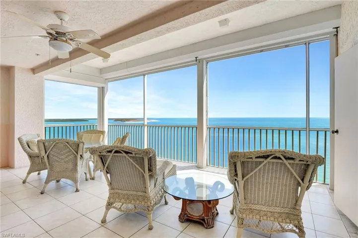 Sunroom / solarium with tile patterned flooring, a water view, and a textured ceiling
