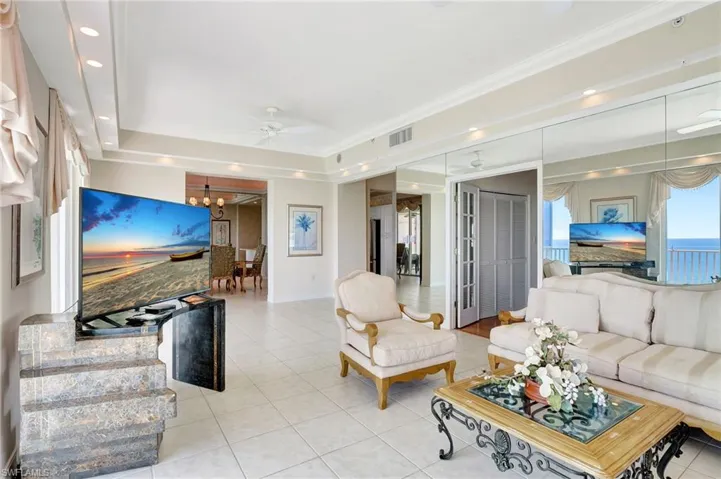 Living room with light tile patterned flooring, visible vents, recessed lighting, and ceiling fan with notable chandelier