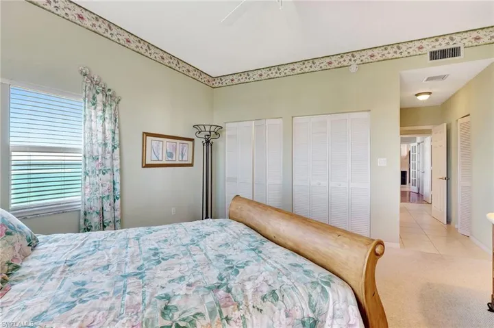 Bedroom with tile patterned floors, carpet floors, a ceiling fan, visible vents, and two closets