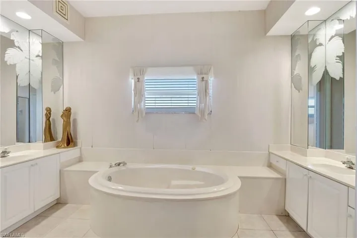 Bathroom with a sink, a garden tub, tile patterned flooring, and two vanities