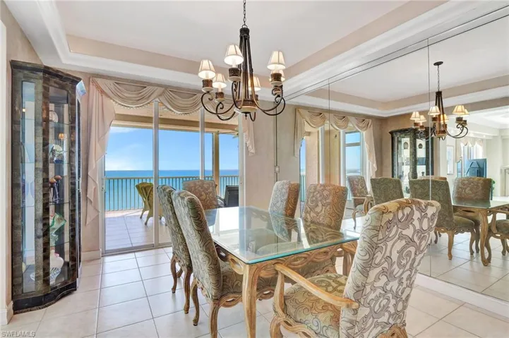 Dining area featuring a tray ceiling, a wealth of natural light, a water view, and an inviting chandelier