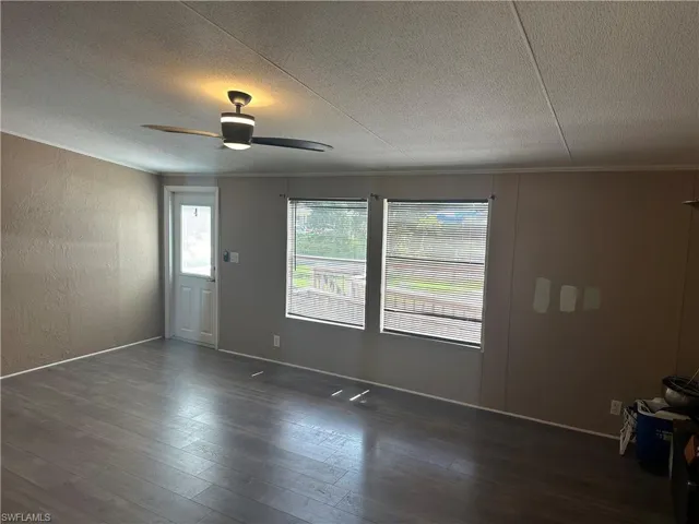 Unfurnished room featuring crown molding, dark hardwood / wood-style flooring, ceiling fan, and a textured ceiling